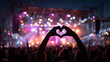 © Alex Alex - Close-up of a viewer's hands folded in the shape of a heart against the backdrop of a concert stage with bright pink light and smoke; a music festival, emotions, unity, and love for music.