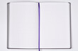 © nahhan - An open notebook with white lined pages and a purple silk ribbon bookmark lies flat on a neutral background featuring colored book edges