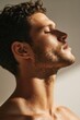 © Anastasiia - Close-up profile of a shirtless man with curly hair and stubble, eyes closed, head tilted back in warm light. Concept Close-up profile, Shirtless man, Curly hair & stubble, Eyes closed, Warm light
