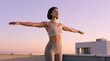 © Budjak Studio - A young woman with a short haircut in sportswear stands on a roof with her arms outstretched.