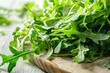 © Olga Ко - Hojas frescas de rúcula verde brillante sobre tabla de madera rústica - Concepto de alimentación saludable de primavera.