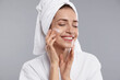 © New Africa - Beautiful woman with hair wrapped in towel and cosmetic product on face against grey background