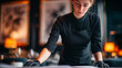 © Maryna - A focused restaurant worker in a sleek black outfit studies a menu, embodying professionalism and dedication in a stylish dining atmosphere.