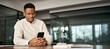 © insta_photos - Busy African American entrepreneur using cell phone working in office. Professional young Black business man holding mobile cellphone looking at cellphone making financial bank payment at work.