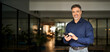 © insta_photos - Happy middle aged older male investor holding mobile phone looking at camera with smartphone at work. Smiling mature business man corporate leader using cellphone standing in office. Portrait.