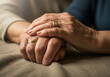 © Shutterbug Haven - Elderly couple wrinkled hands holding tightly showing lifelong commitment ring.