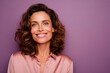 © Enrique - Happy middle-aged woman smiles brightly. Attractive person wears pink silk shirt against purple backdrop. Brown wavy hair, fair skin. Looks positive, confident. Confident female professional portrait