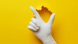 © Alexandr Efimov - White gloves poking through a cutout on a solid yellow background.