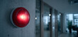 © hestywinarni - Red fire alarm light mounted on wall in indoor building corridor with glass doors and reflections