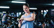 © P2000/peopleimages.com - Exercise, smile and watch with woman in gym for performance tracking, results or satisfaction. App, fitness and time with happy person in health club for challenge, improvement or training review