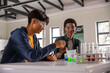 © wavebreak3 - African american teenage male students handling pipettes and beakers mixing liquids at lab