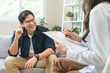 © KMPZZZ - Psychology, depression. smile asian young male, man patient mental sitting on couch, explained symptom with psychologist, psychiatrist while doctor woman taking notes at clinic. Encouraging, therapy.