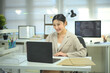 © Prathankarnpap - Smiling female programmer working on laptop at modern office desk, software development and professional tech
