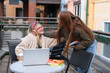 © Iryna - Two friends study together on a balcony in a city during daylight hours with laptops and books