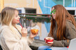 © Iryna - Friends enjoy drinks at a cafe while chatting in a colorful outdoor setting