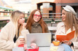 © Iryna - Friends meet for study session at cafe on sunny day in city center with laptops and drinks on table