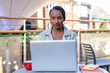 © Iryna - Woman working on laptop at outdoor cafe in city during sunny day
