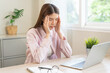 © KMPZZZ - Stressed, exhausted asian young woman having migraine symptoms headache, bored sitting work long time, suffering from dizziness, holding head with hand office syndrome. Health care problem of worker.