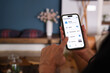 © Ladanifer - Woman using smartphone app to control lights, thermostat, security and camera in her smart home