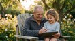 © Anchalee - Happy grandfather and granddaughter using digital tablet and stylus in sunny garden. Senior man teaching young girl digital art on tablet sitting in wooden chair outdoors during summer sunset.