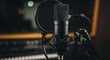 © CreativeIMGIdeas - Close-up of professional condenser microphone setup in a dark recording studio, featuring a shock mount and pop filter, ready for podcasting, vocal recording, or broadcasting.