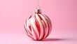 © Vee - A single candy cane striped Christmas ornament hangs against a soft pink background.