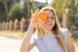 © luismolinero - Young blonde woman at outdoors holding an orange with happy expression