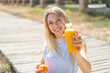 © luismolinero - Young blonde woman at outdoors holding an orange and an orange juice