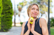© luismolinero - Young blonde woman at outdoors holding an avocado