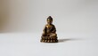 © MakeitEasy - A statue of a Buddha seated in a meditative pose against a plain background. The statue is ornate, with intricate detailing its attire and the peaceful expression on its face