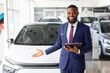 © Prostock-studio - Portrait Of Handsome Black Manager In Suit Posing At Workplace In Car Dealership Center, Smiling Professional African American Salesman Standing Near Luxury Auto, Advertising New Vehicle, Copy Space