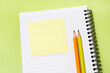 © soya - Flat lay notebook with sticky note and pencils on yellow green background