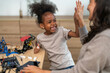 © Art_Photo - Happy african american girl high five with mother after building robot at home, Child learning STEM coding and engineering, education, science technology, family teamwork and success concept