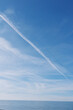© SHOTPRIME STUDIO - Blue sky over calm ocean with a distant horizon and a white contrail streak, gentle clouds, serene seascape conveying tranquility and expansive outdoor scenery.