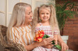 © Pixel-Shot - Cute little girl and her grandmother with bouquet of tulip flowers at home
