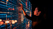 © Rendara Studio - Woman reaching toward complex digital data wall interface