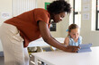 © Wavebreak Media - African American teacher helping school-age girl viewing tablet in blue folio case in classroom