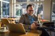 © Miljan Živković - Smiling man working on laptop in cafe enjoying water