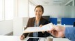 © Gayan - Smiling Southeast Asian professional woman in black blazer during job interview or business meeting in bright modern office, receiving document from colleague, corporate career concept.