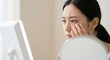 © Gayan - Concerned Young East Asian Woman Checking Dark Circles and Under-Eye Bags in Mirror Indoors, Skin Care and Fatigue Concept, Morning Routine with Tired Mood in White Tank Top