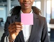 © Pro - Woman in suit holds pink sticky note with office background