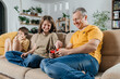 © Westend61 - Dad and kids play video games together on sofa in living room