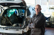 © pressmaster - Portrait of middle aged Caucasian man standing with arms crossed in front of disassembled car in auto repair shop, looking at camera with confident expression