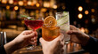 © Shootdiem - Three hands clink elegant zero-proof cocktails garnished with herbs and fruit, symbolizing modern alcohol-free nightlife for young adults.