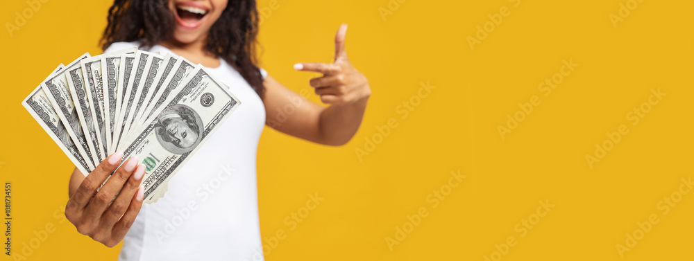 Loan, credit concept. African american woman holding bunch of money, standing over yellow studio background, panorama with empty space. Happy black lady having cash, got loan for business