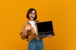 © Prostock-studio - Surprised young woman pointing at laptop with empty screen, standing over yellow background. Emotional lady with computer over studio wall. Mockup image