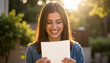 © Silva - Young woman smiling while reading letter outdoors in sunlight