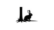 © Nyadong - Silhouette of a rabbit hiding behind a tree trunk on white background.
