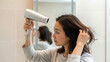 © soojin - A woman drying her hair in the bathroom.