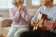 © MIND AND I - Happy Senior Couple Enjoying Retirement Together Playing Musical Instruments at Home in Bright Sunshine